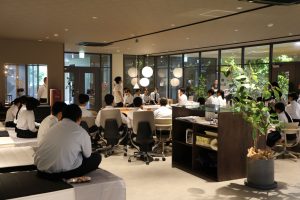 ショールームでベッドの説明を真剣に聞く高校生たち